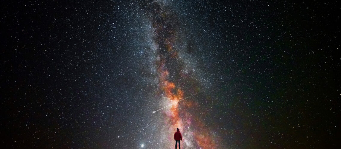 Man on top of a mountain observing the universe