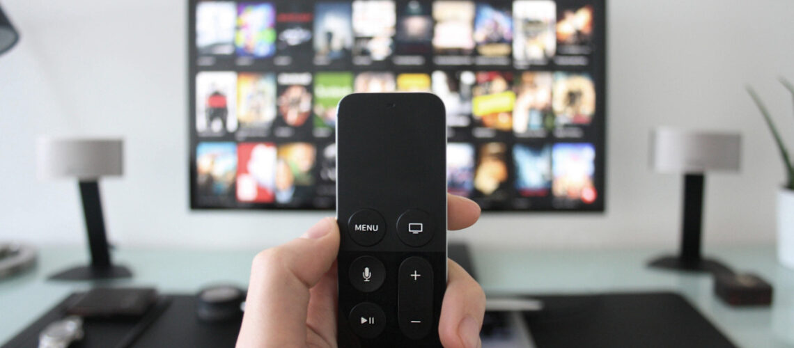 Person holding a remote control watching Netflix