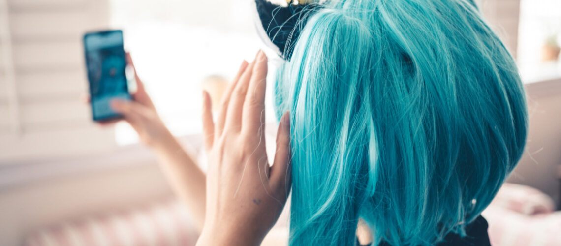 girl wearing a turquoise wig, taking a selfie.